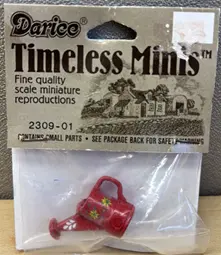 a Darice Timeless Minis package with a red watering can figurine inside